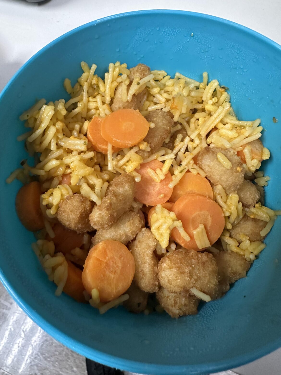My kids’ dinner leftovers often become my lunch for work. Today, it’s this culinary concoction: popcorn shrimp, cheesy rice, and carrots.