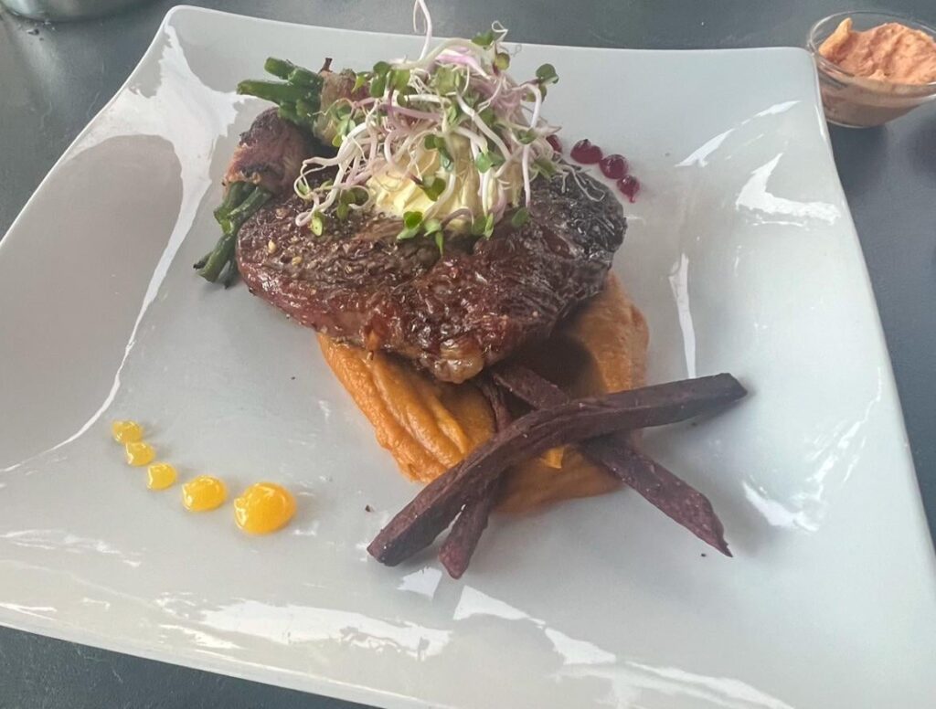 Entrecôte served with beans wrapped in bacon, sweet potato puree and two red beet fries