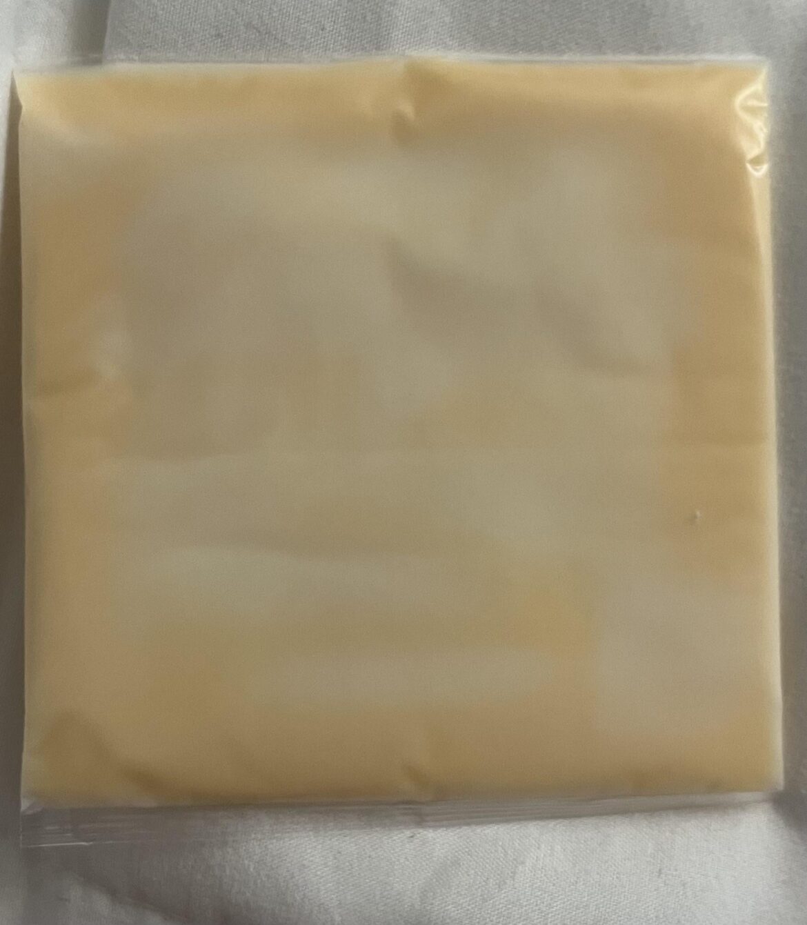 Why is my newly opened yellow American cheese pack this white color?