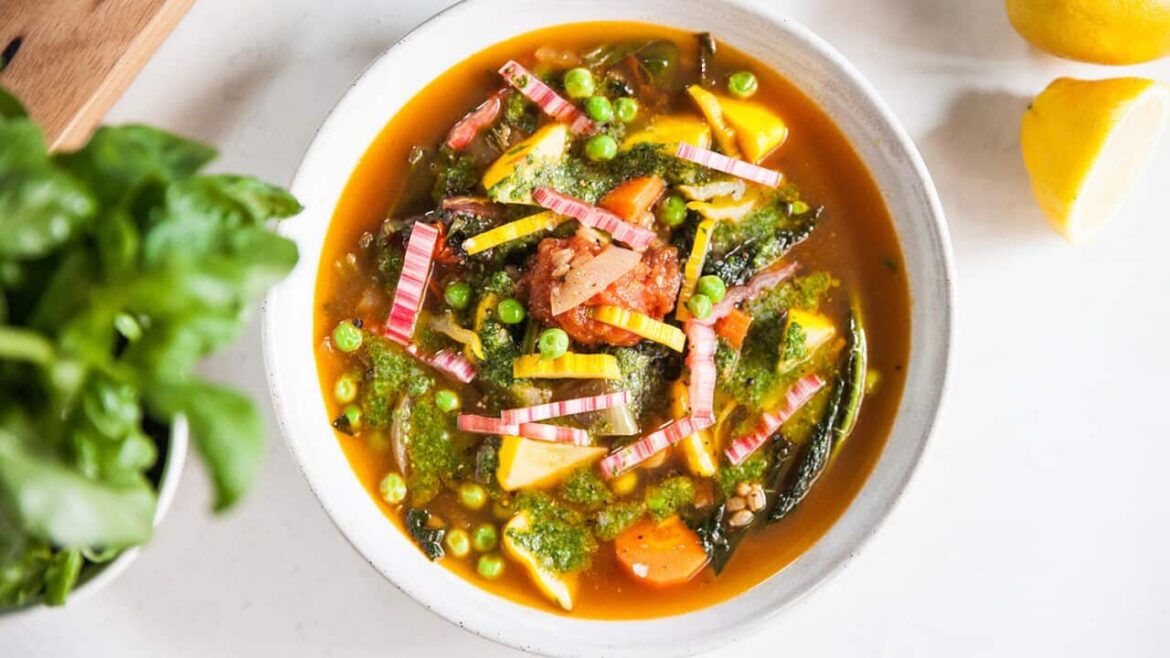 17 great vegetarian recipes from Freshly Picked with Simon Toohey A colourful chunky vegetable soup in a white bowl, topped with a green sauce garnish, is seen from overhead.