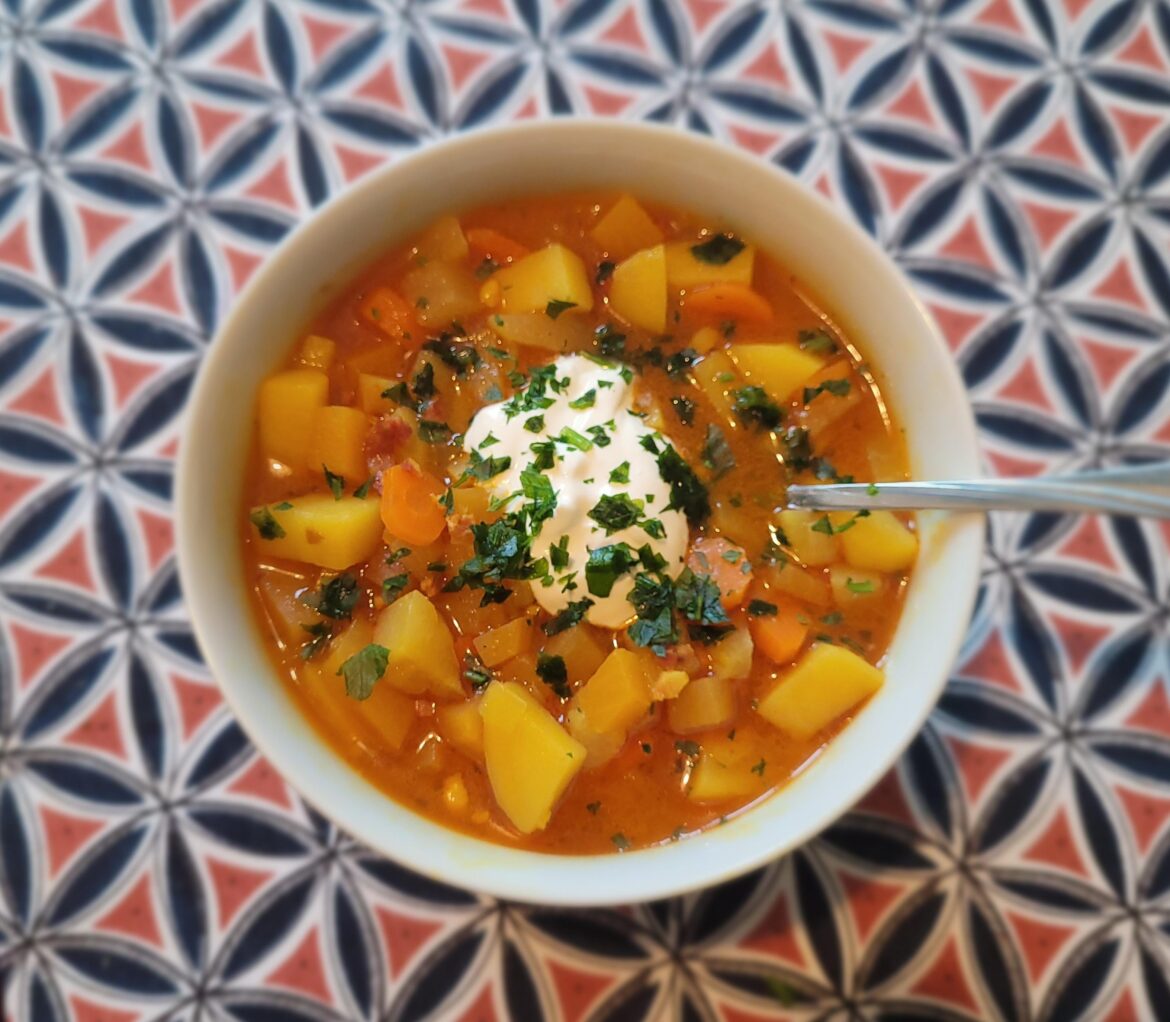 Hearty root veggie soup topped with sour cream and parsley