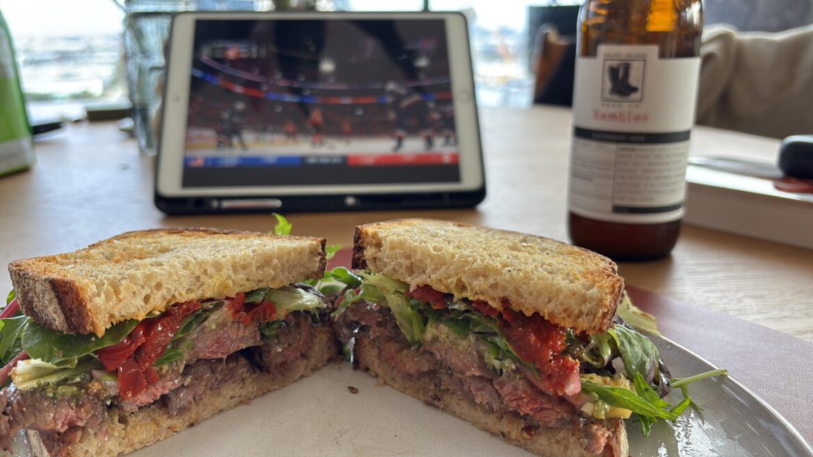 Steak sandwhich with blue cheese, pickled onion, roasted peppers, mixed greens, pesto, mustard, mayo on Sourdough