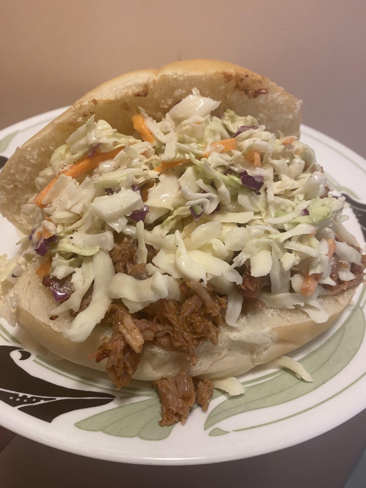 Smoked pulled pork sandwich overloaded with coleslaw.
