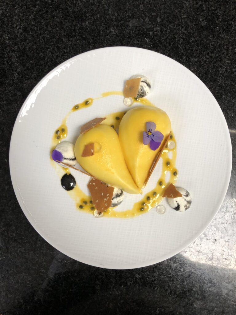 Passionfruit mousse, black sesame praline + sponge + tuile, thickened fresh passionfruit with ginger