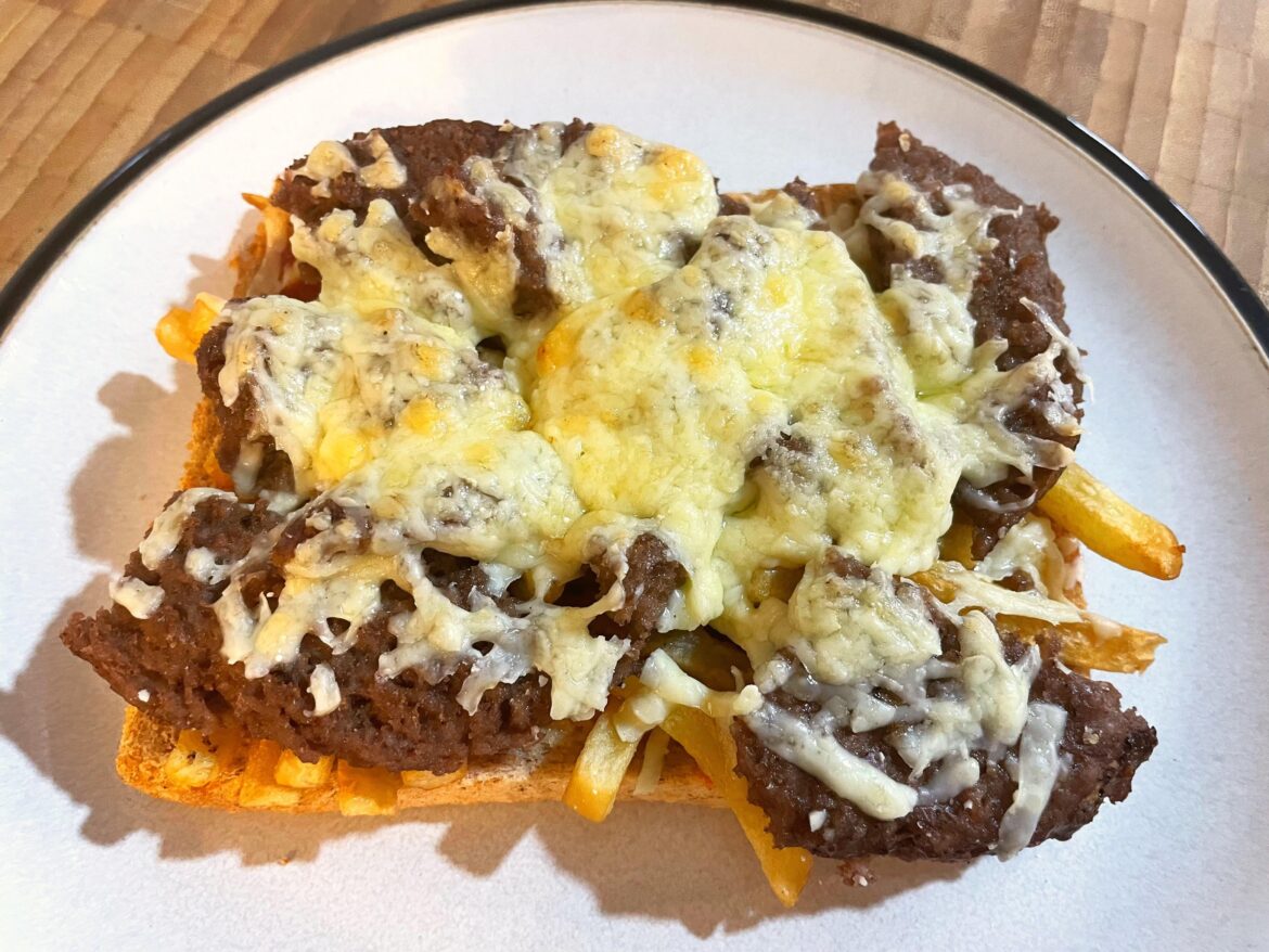 Deconstructed cheese burger on a bed of fries on toast.