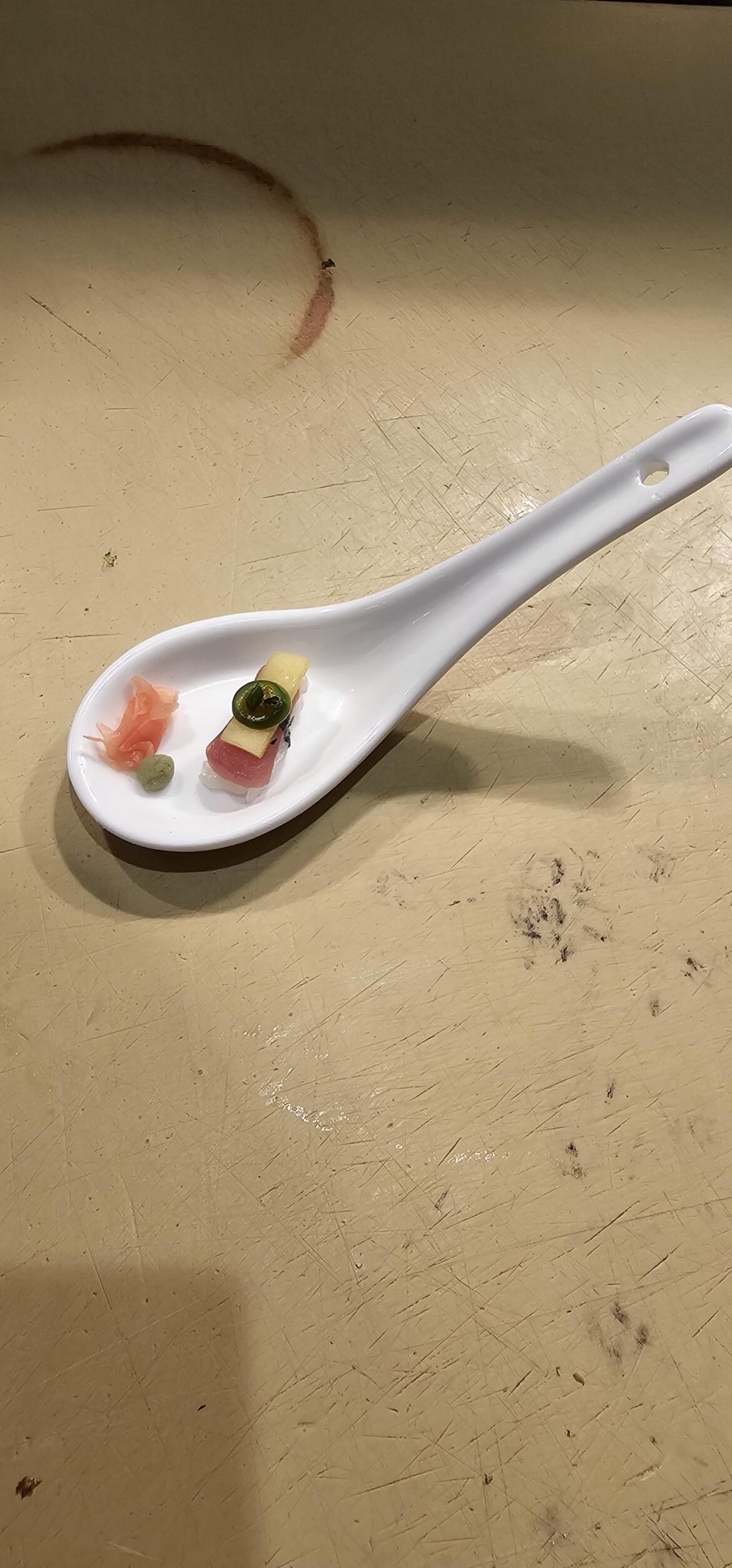 A morsel of tuna nigiri topped with succulent(?) mango and a jalapeño pence.