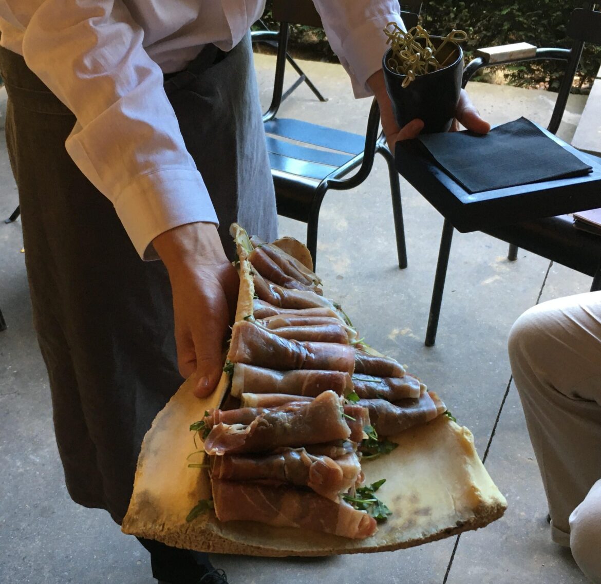 Cured ham with arugula served on an old dirty bone
