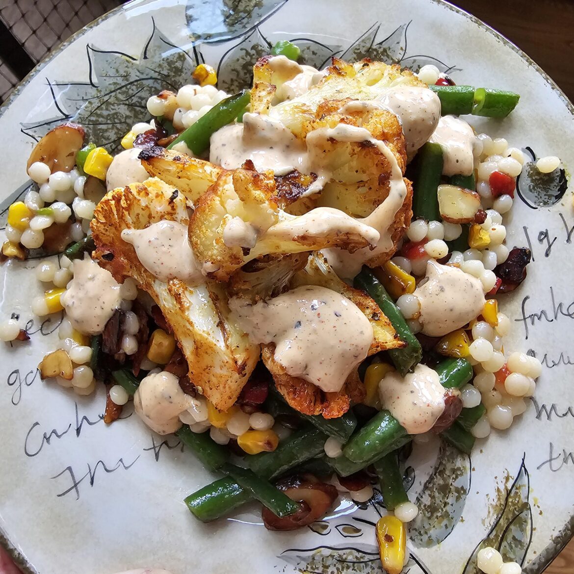 Blackened cauliflower w/ couscous and sautéed veggies with almonds and an apricot jam drizzle. Topped with a Cajun sauce