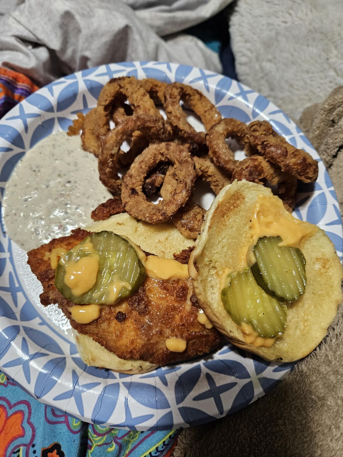 Spicy chicken sandwich on an onion roll with chipotle mayo and onion rings with parmesan garlic sauce