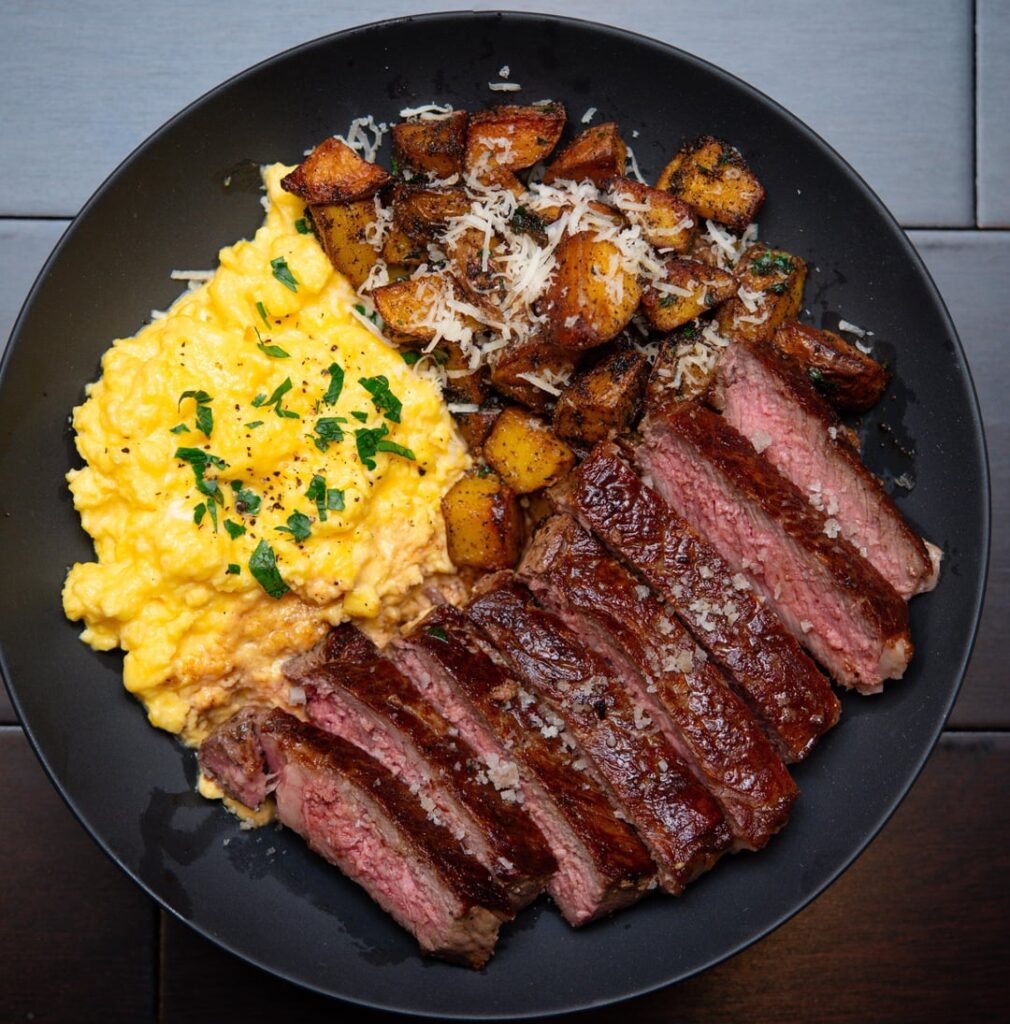 Ribeye steak, eggs scrambled with crème fraiche and garlic Parmesan fried potatoes in butter.