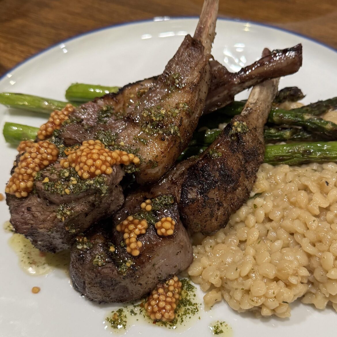 Sous vide rack of lamb seared to finished. Topped with mustard seeds and chimichurri.