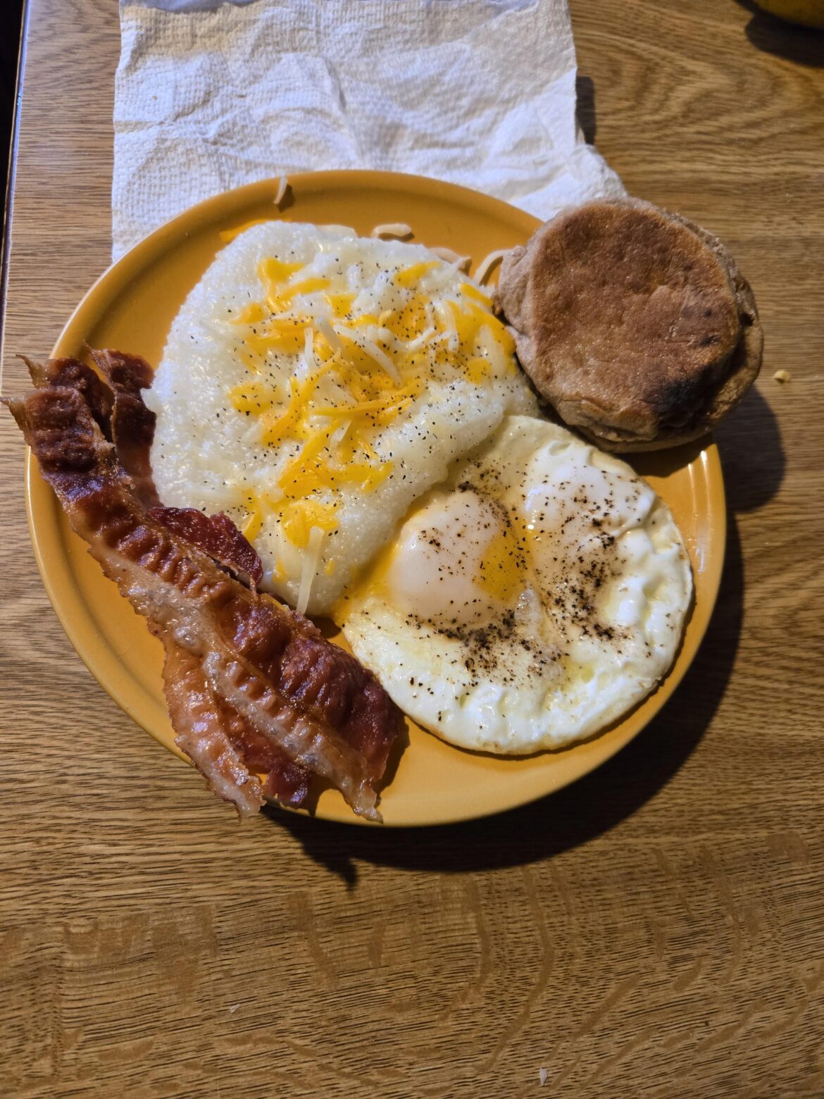 Eggs, bacon, grits and an english muffin.