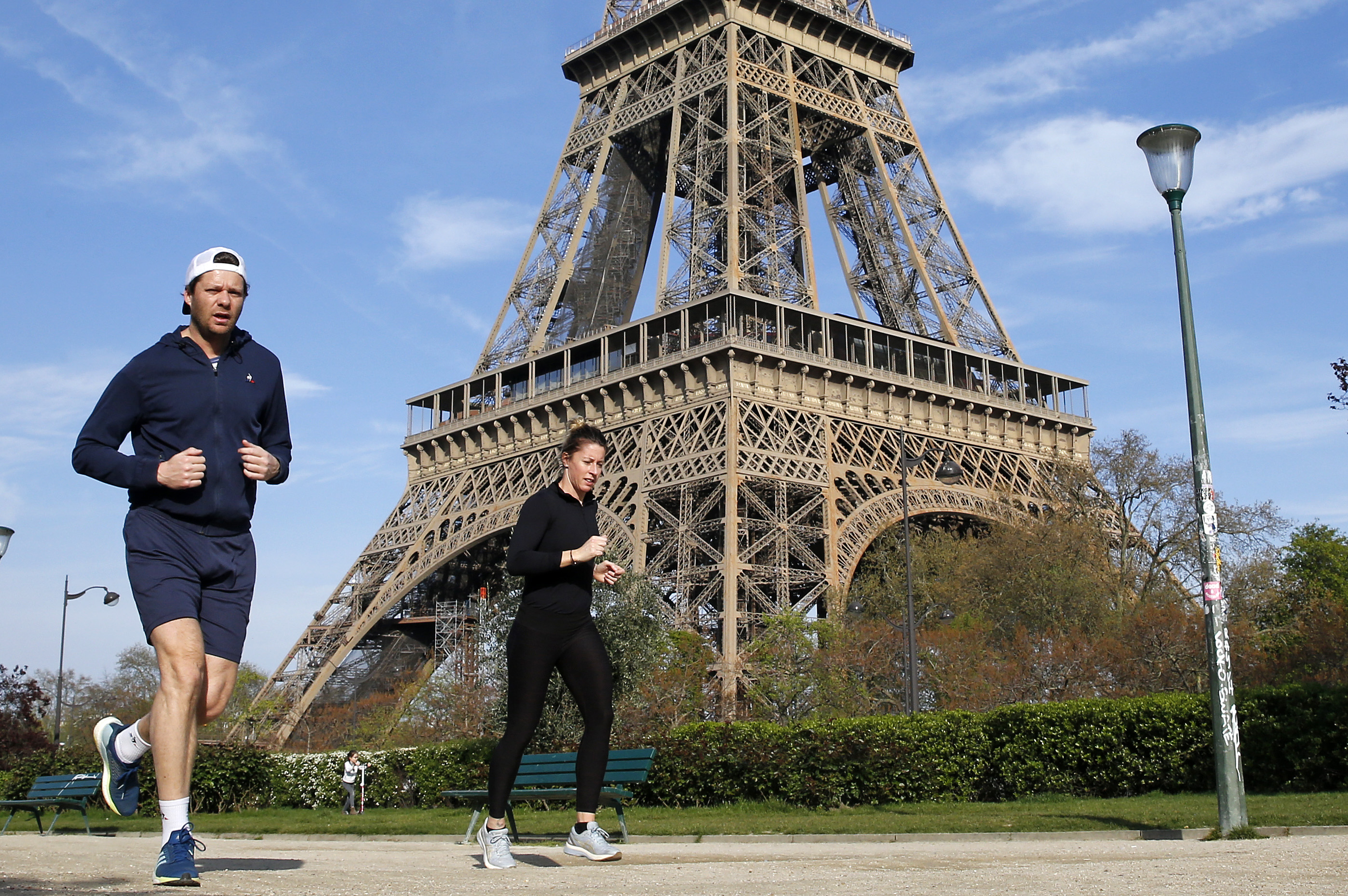 Two people jogging in front of the Eiffel Tower during a lockdown.