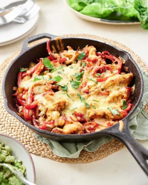 A picture of a chicken fajita bake topped with melted cheese in a cast iron frying pan