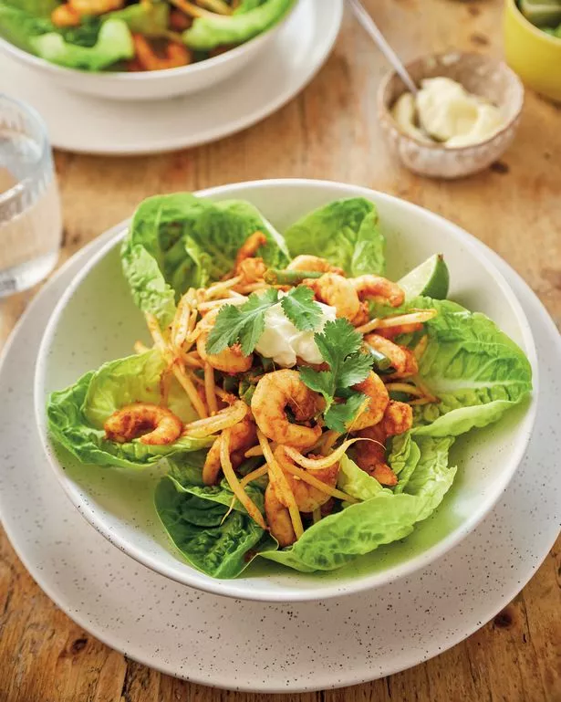 A picture of zingy bang bang prawns in a bed of lettuce leaves in a white bowl