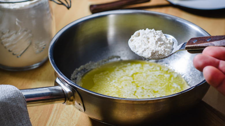 Pan of melted butter, with a spoonful of flour being held above it