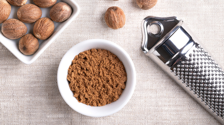 Ground nutmeg in bowl, with grater and whole nutmeg