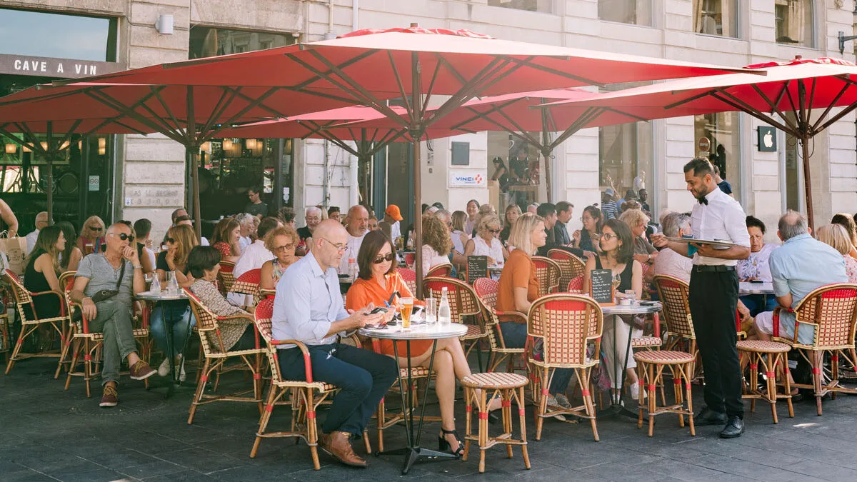 People enjoying drinks and snacks at a café in Bordeaux