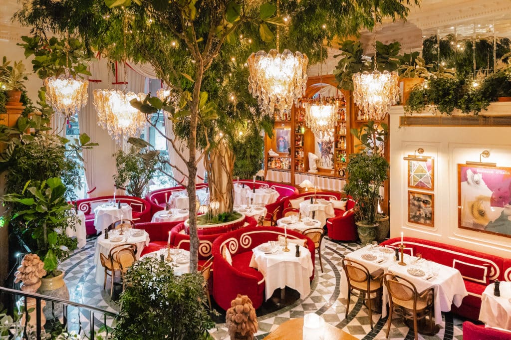 the foliage filled fancy interiors of jacuzzi restaurant, with red armchairs, white linened tables, and quirky chandeliers