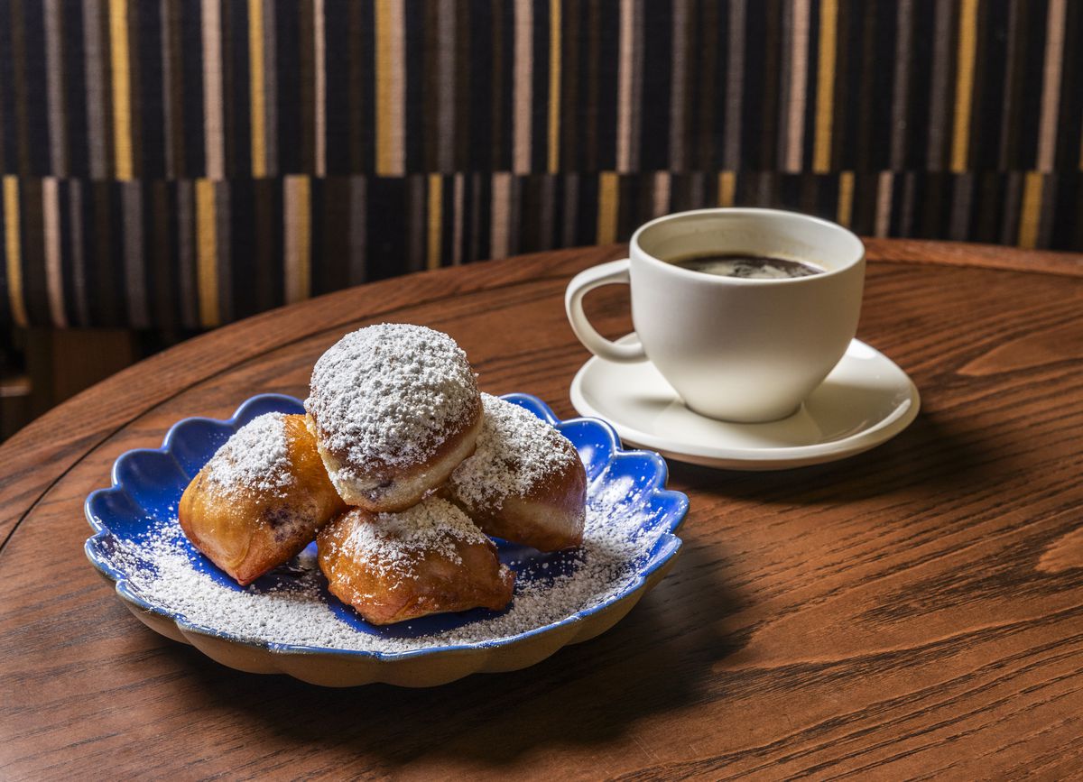 A plate of beignets with a side of coffee at Perseid.