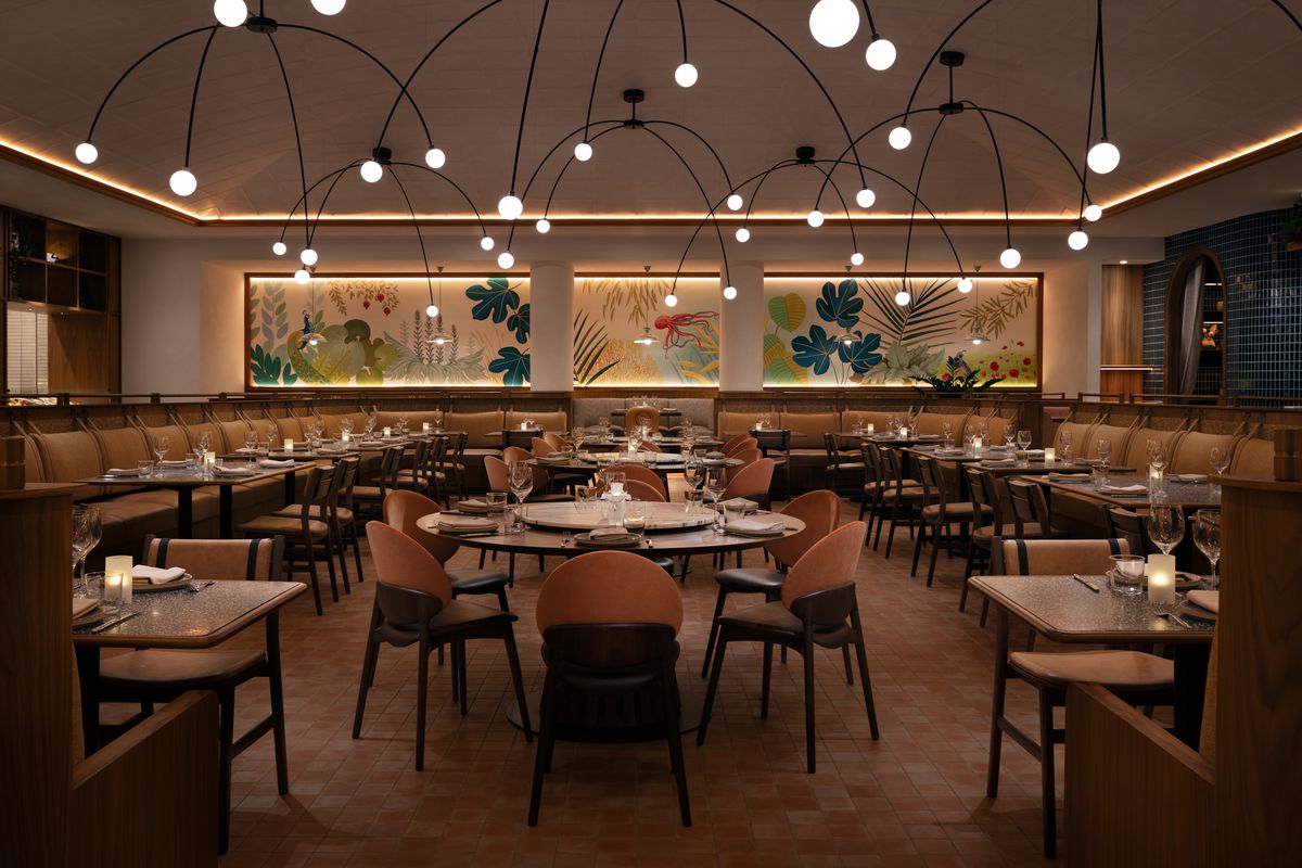 The interior of a Greek restaurant with a mural and table seating.
