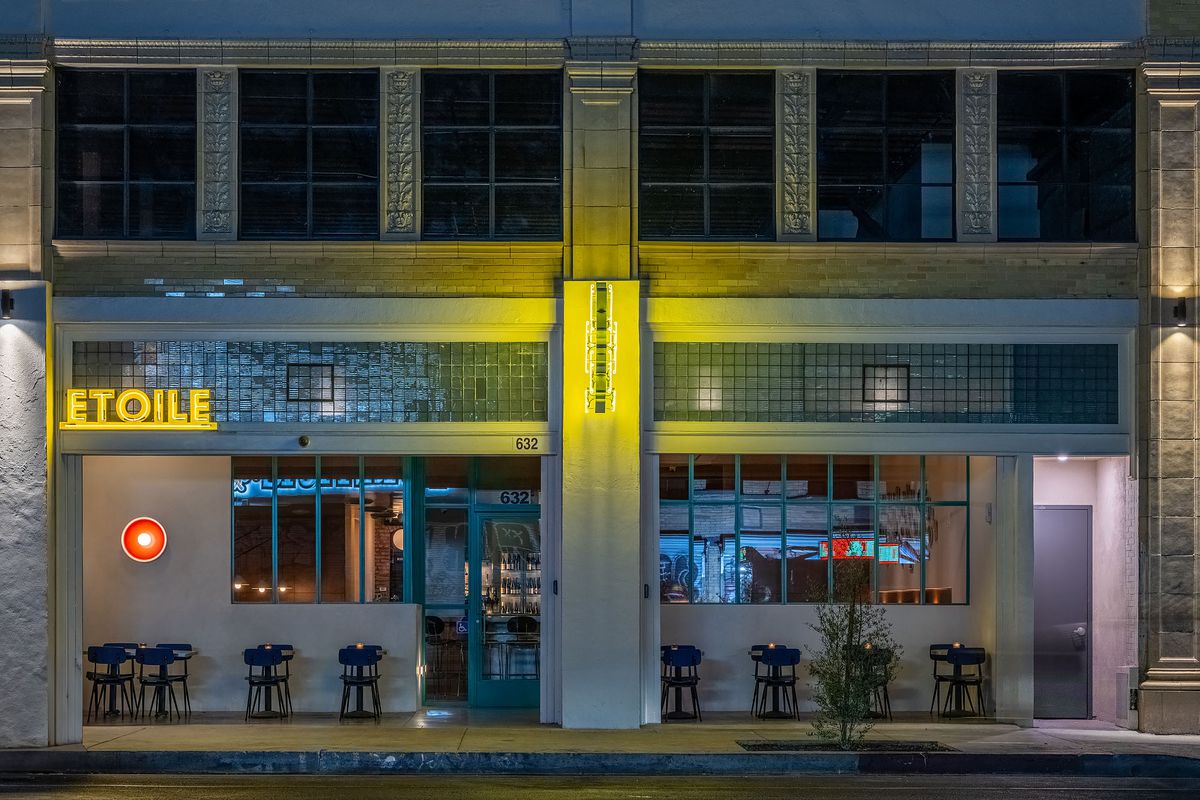 The exterior facade at Bar Etoile with yellow neon lights for its name and three stars.