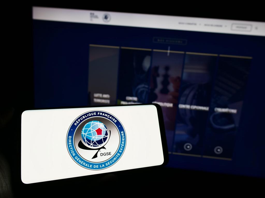 Person holding mobile phone with logo of Direction Generale de la Securite Exterieure (DGSE)