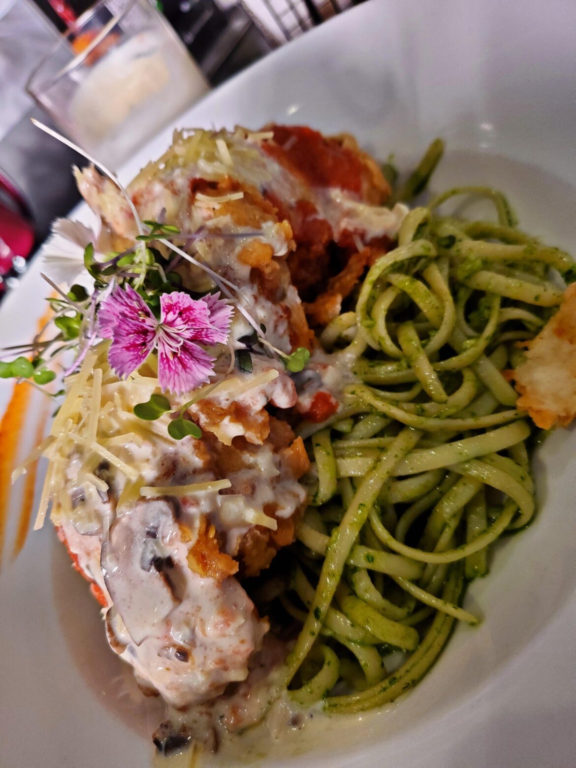 Chicken parmesan over pesto pasta