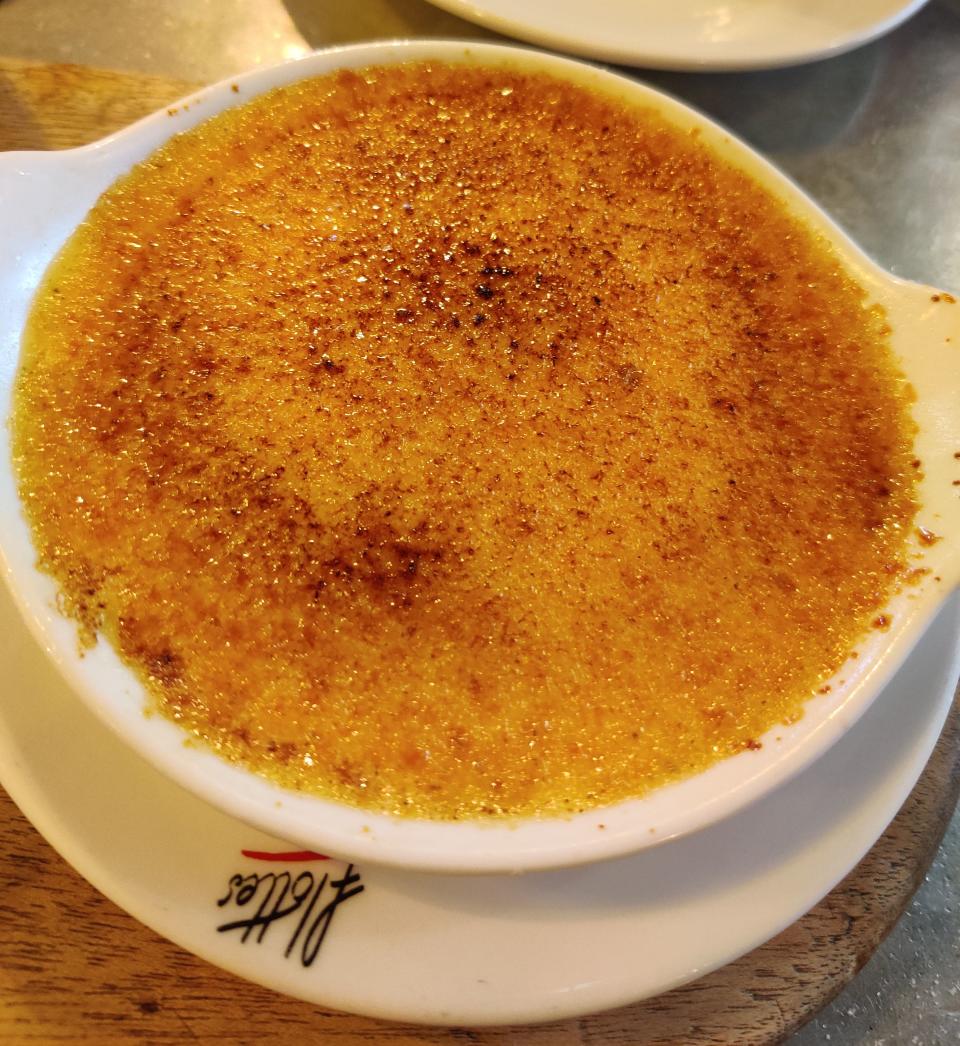 A dish of crème brûlée with a caramelized sugar topping served on a white plate