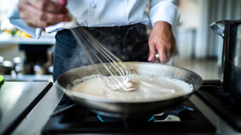 Chef preparing béchamel sauce in commercial kitchen