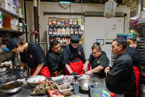 Local Ocean kitchen staff demonstrate the proper way to shuck oysters in a restaurant kitchen