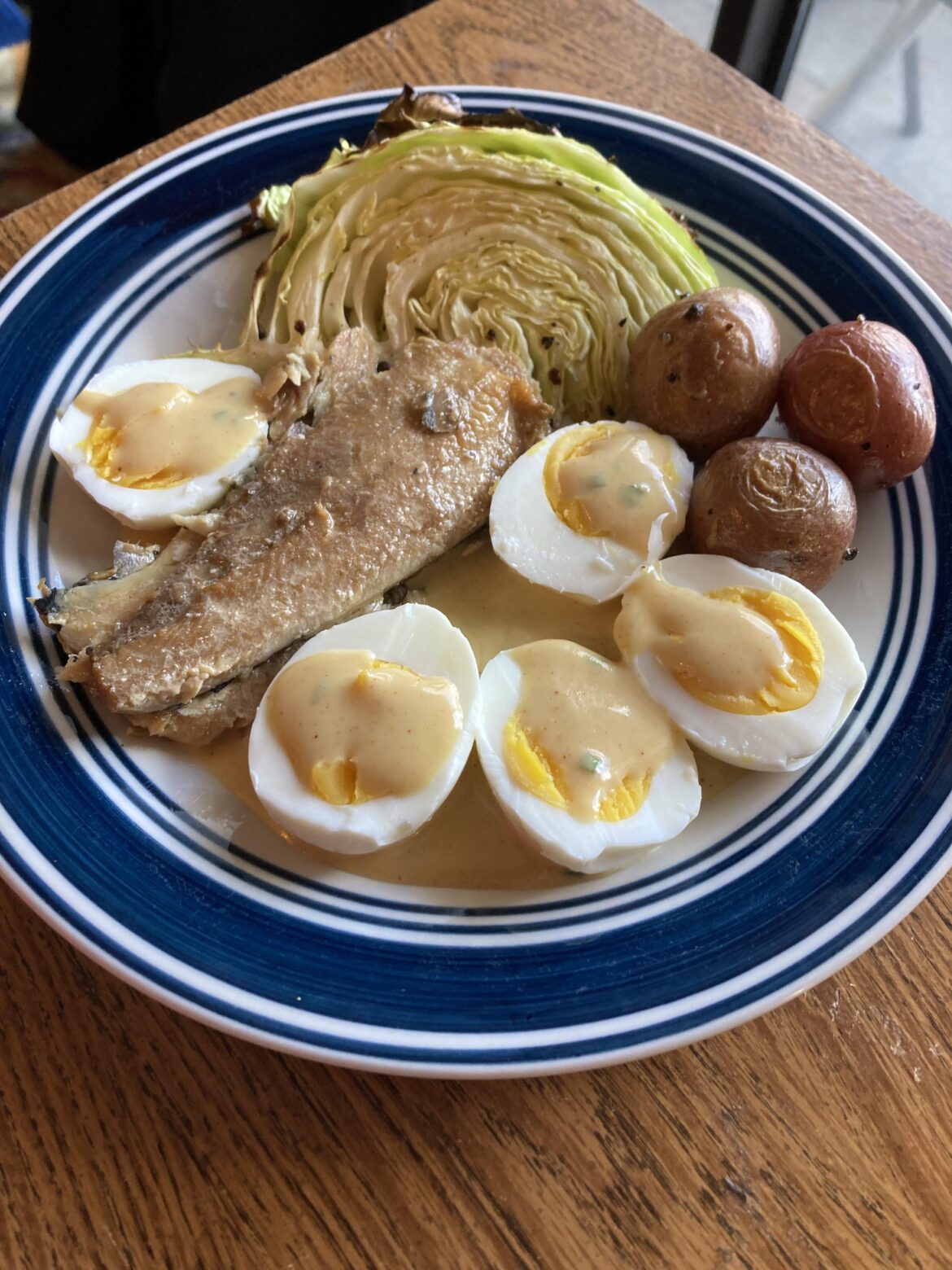 Eggs with mustard sauce, kippers, roasted cabbage and potatoes