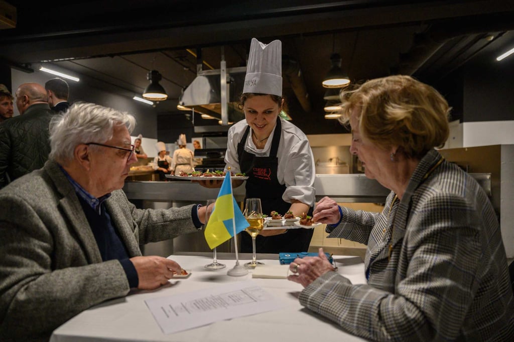 A trainee chef from Mariupol, Ukraine offers food to diners after undertaking the training programme. Photo: AFP