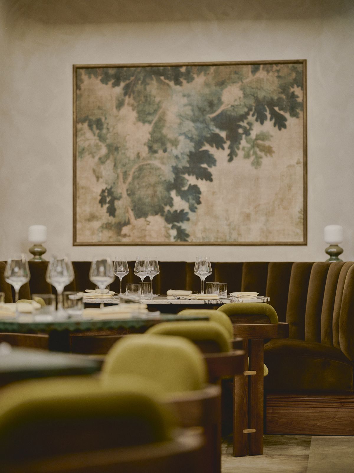 Velvet banquettes and a large painting of leaves. 