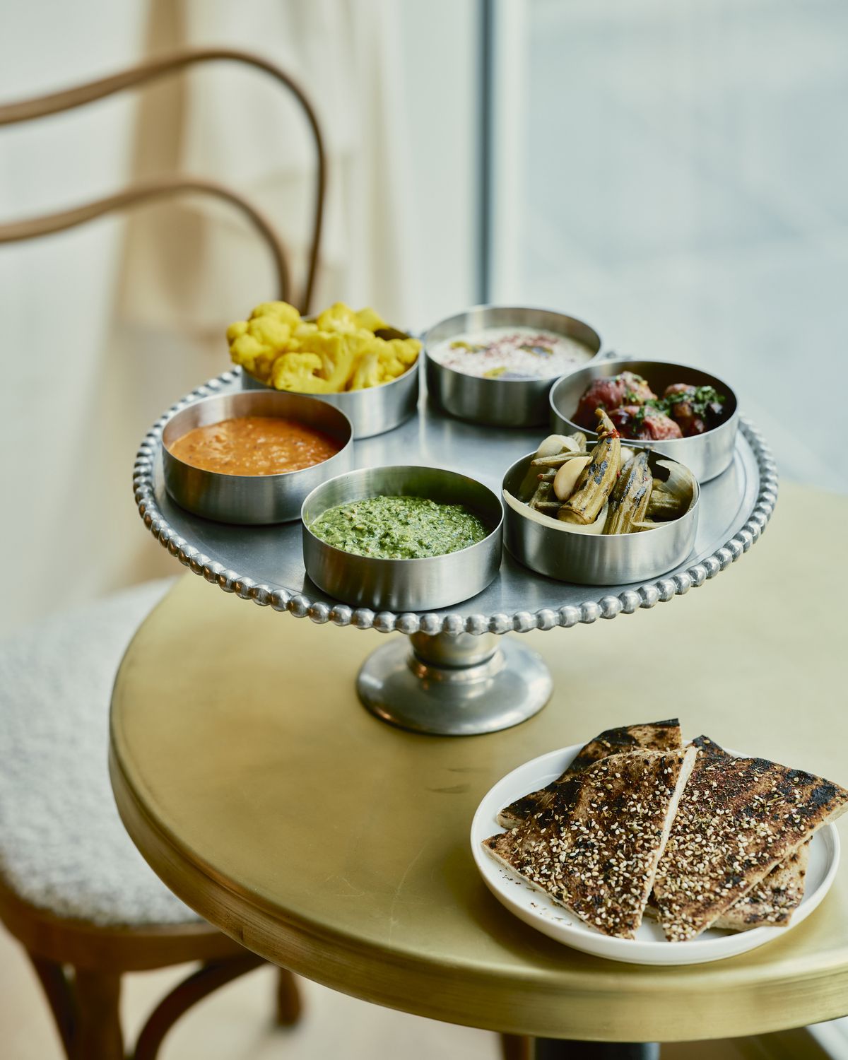 An assortment of dips and pickled items on a silver tray. 