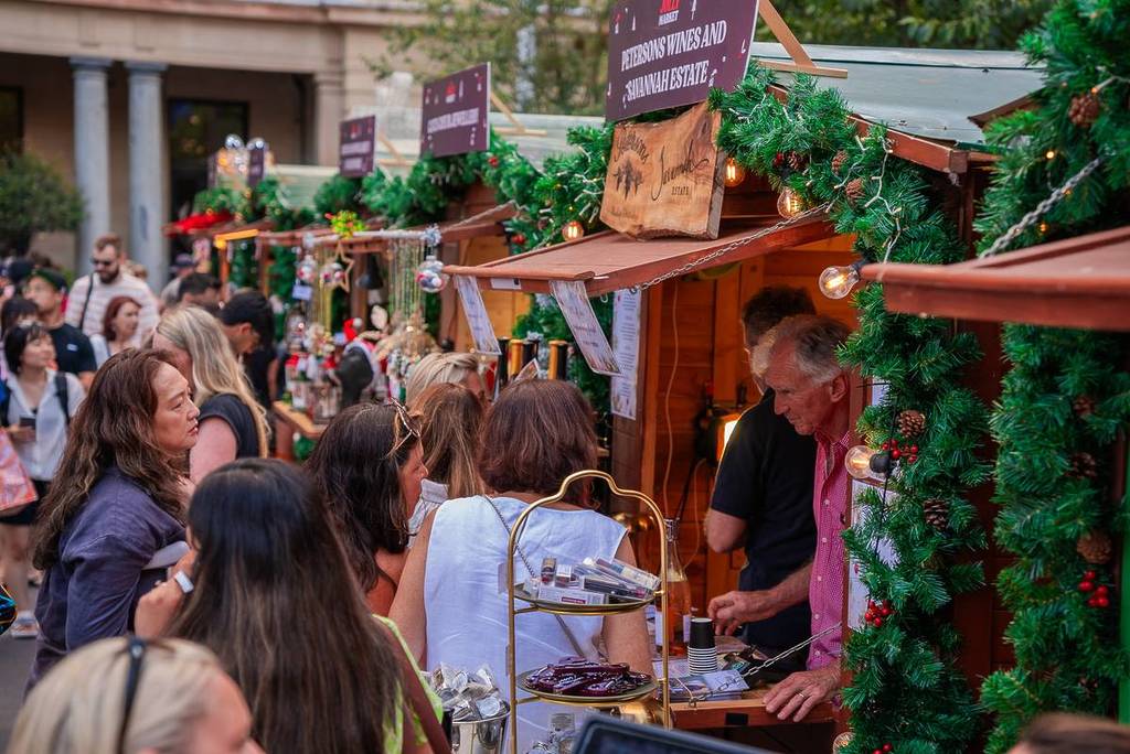 People shopping at a food stall in a wooden hut at Le Jolly Market