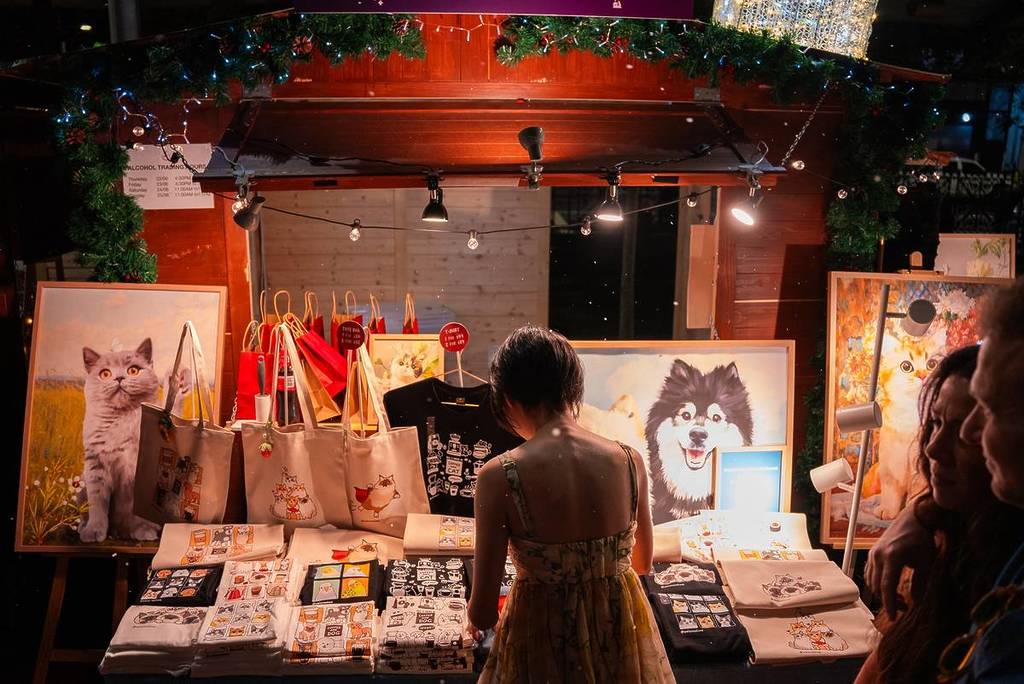Person browsing at an art stall at Le Jolly Market