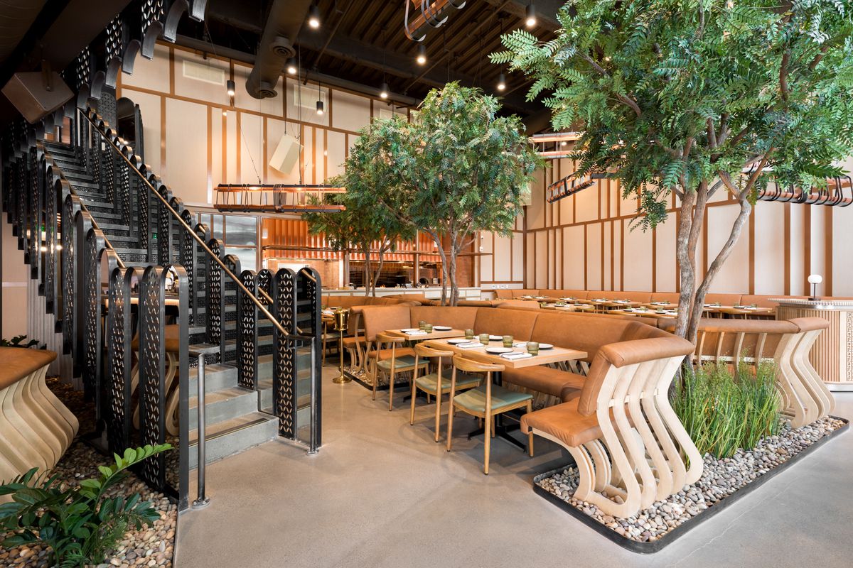Looking towards the stairs out at a dining room with trees between booths.