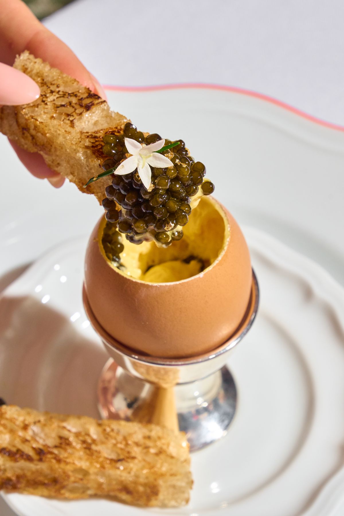 A soft egg with a piece of toast covered in caviar. 