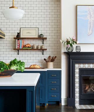 kitchen with Subway tiles, blue cabinets, marble countertops and fireplace