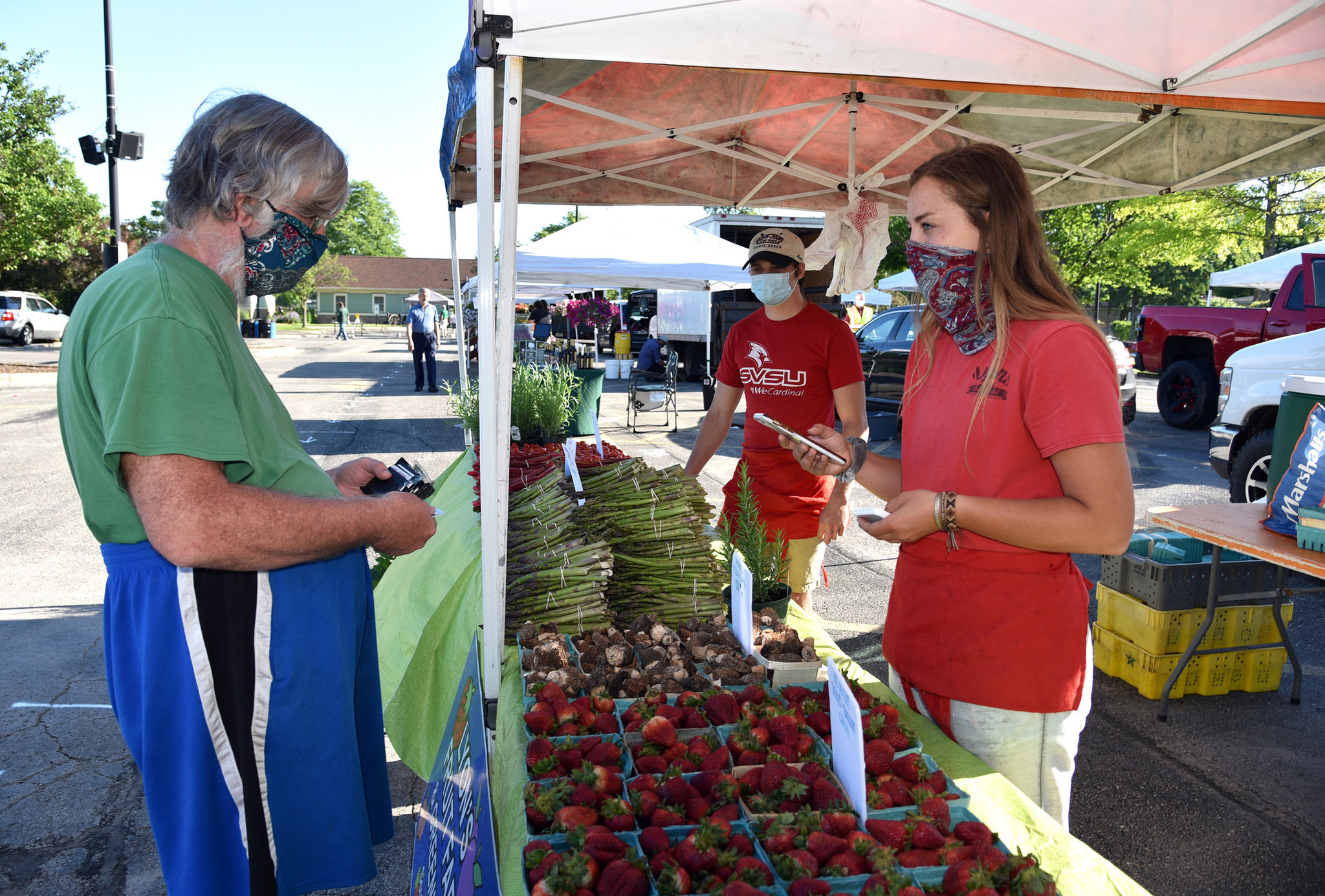 The market has just opened. From left, patron Ken Baird of Morton Grove exchanges a transaction with vendors Chris Kerber and Frances Lyons of Lyons Fruit Farm & Greenhouse of South Haven, Michigan. Images from the opening day of the Morton Grove French Market in Morton Grove on June 6, 2020 at 6140 Dempster St.