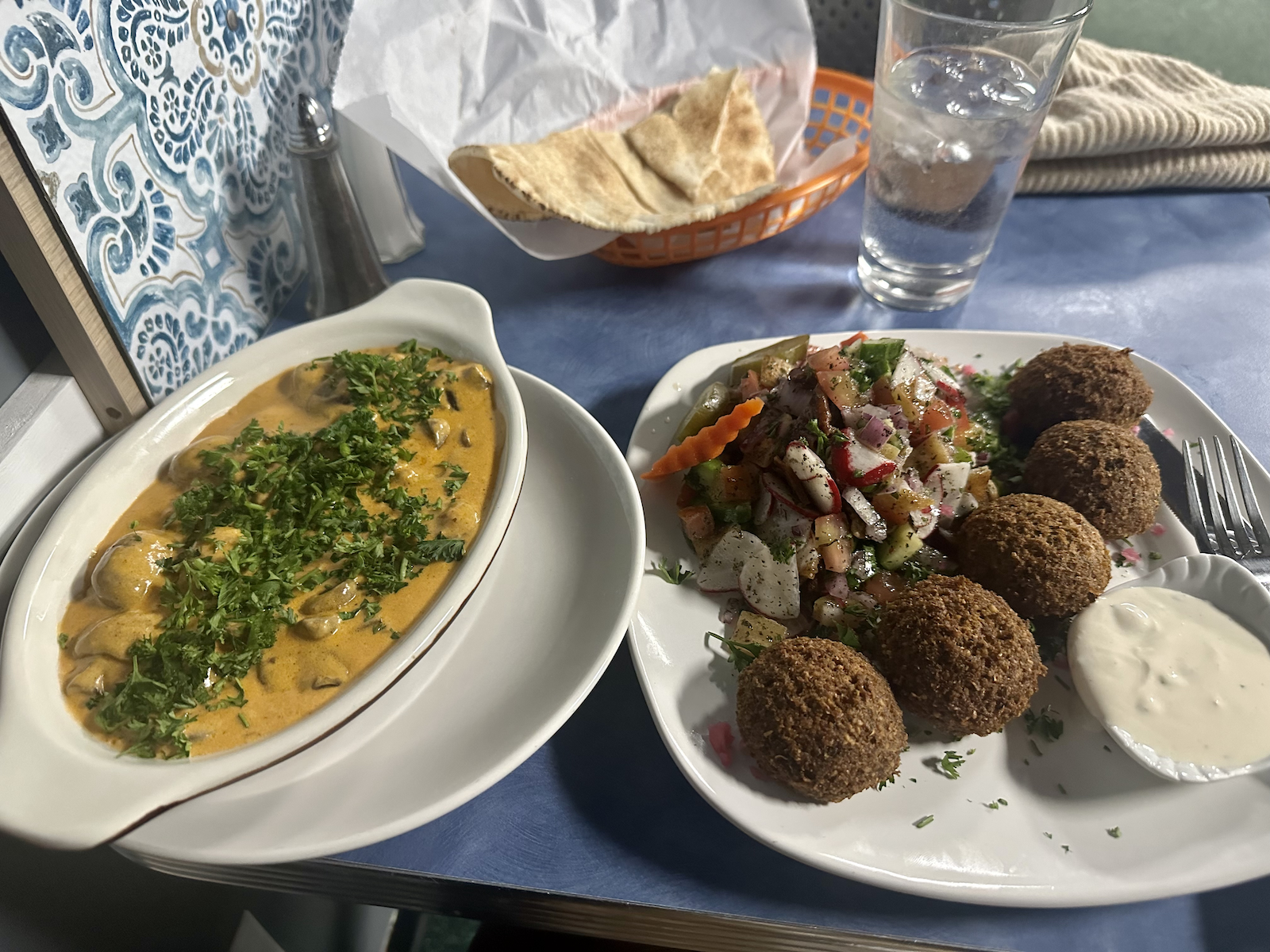 A dish of mushrooms in sauce and a plate of falafel with salad.