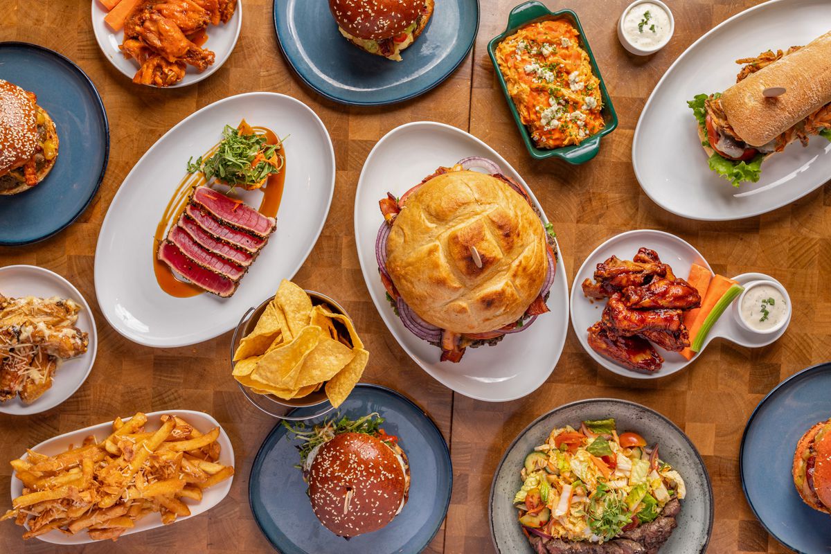 An overhead picture of food like burgers, ahi tuna, and wings.