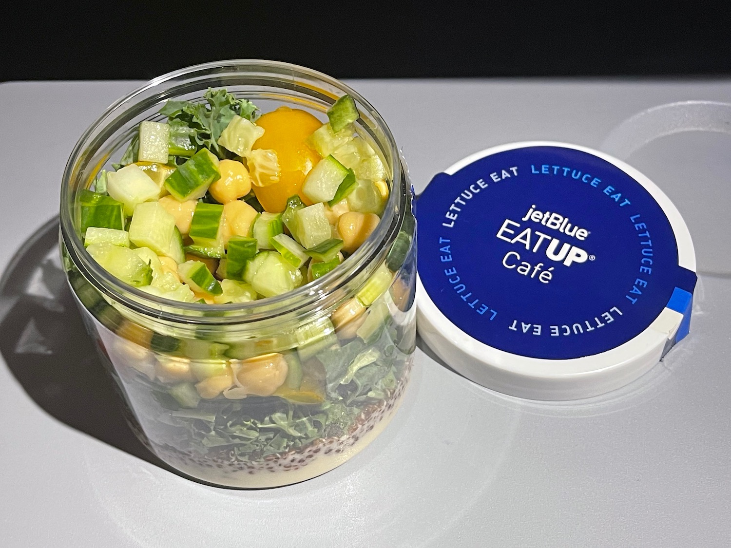 a jar of salad with vegetables and a blue lid