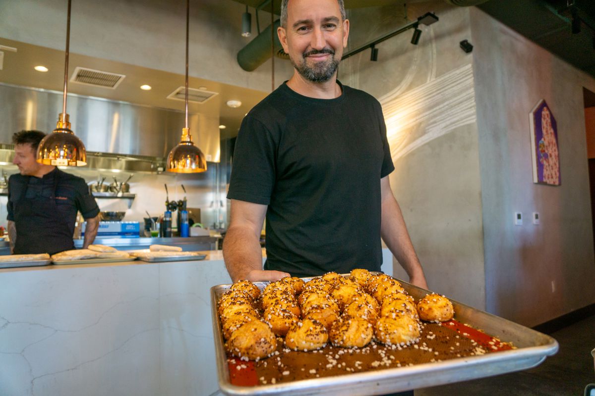 A man holds up a tray of fresh pastries called chouquette.