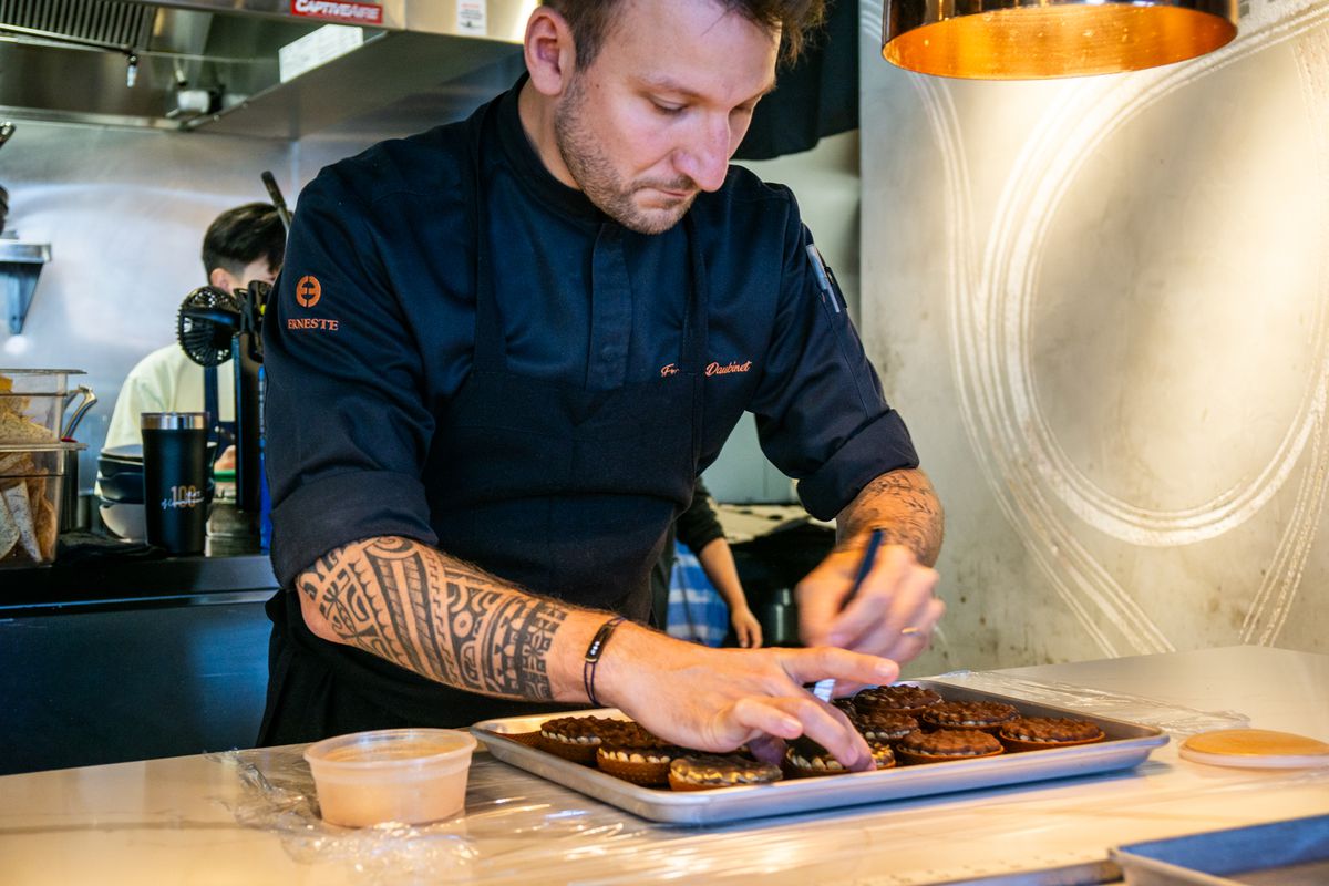 Pastry chef Francois Daubinet wearing a black chefs coat and making pastries.
