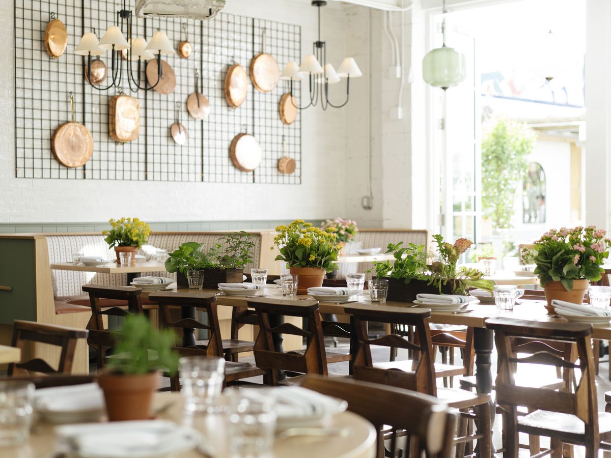 Wooden tables with wooden chairs, topped with small potted plants.