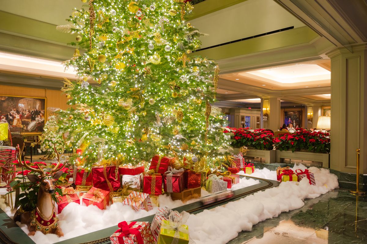 A large, lit up Christmas surrounded by fake presents in a hotel lobby.