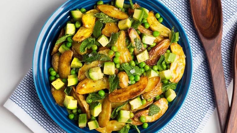 Bowl of avocado and potato salad with serving spoons