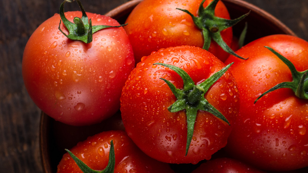 A bunch of tomatoes in a bowl on a wooden background.